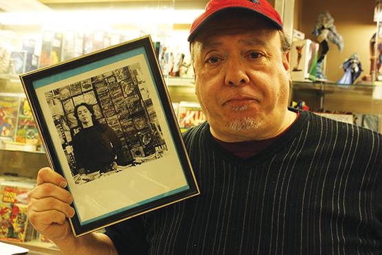 Novak St. poses with a photo of his younger self as a comic book aficionado.
